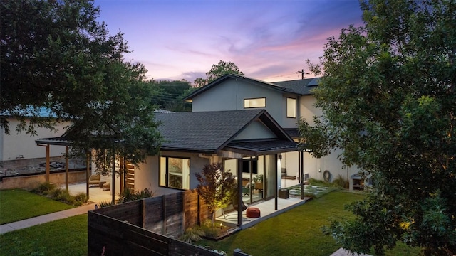 2500 Cedarview Dr, Austin, TX 78704 - back of house at dusk featuring solar panels, a shingled roof, stucco siding, and a patio area