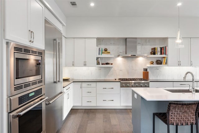 2500 Cedarview Dr, Austin, TX 78704 - kitchen featuring wall chimney range hood, appliances with stainless steel finishes, open shelves, dark wood-type flooring, and backsplash