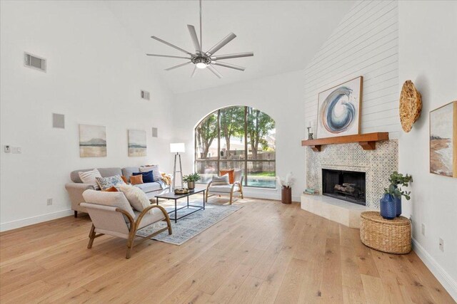 3313 Oxsheer Dr, Austin, TX 78732 - living room featuring high vaulted ceiling, a ceiling fan, light wood-style flooring, a large fireplace, and baseboards