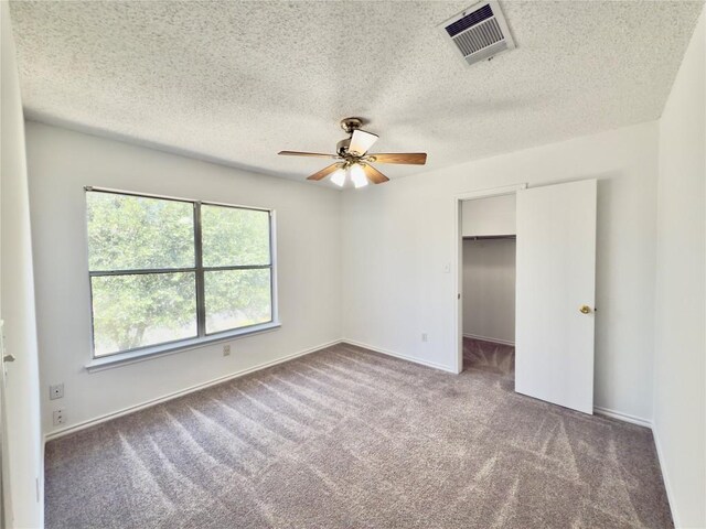 7817 Marble Ridge Dr, Austin, TX 78747 - unfurnished bedroom with carpet flooring, a spacious closet, a textured ceiling, baseboards, and ceiling fan