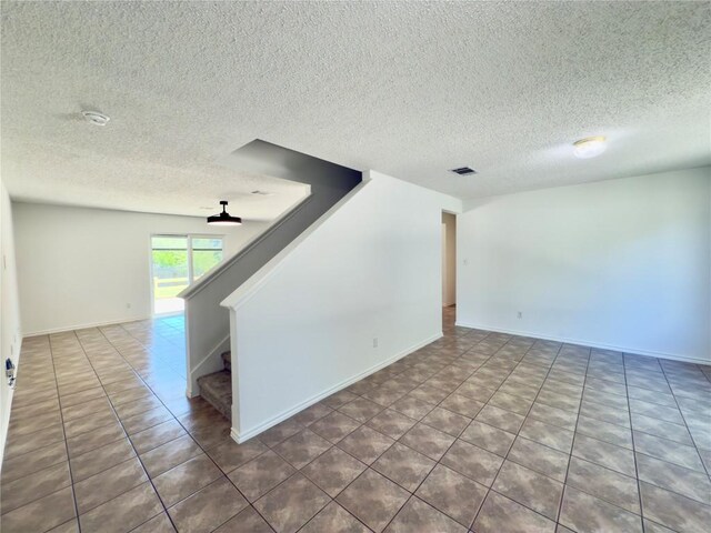 7817 Marble Ridge Dr, Austin, TX 78747 - empty room with a textured ceiling, stairs, tile patterned floors, and baseboards