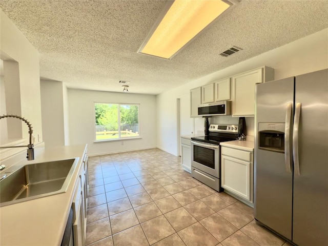 7817 Marble Ridge Dr, Austin, TX 78747 - kitchen featuring stainless steel appliances, a sink, light tile patterned floors, a textured ceiling, and light countertops