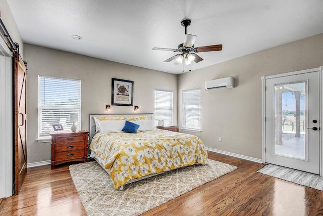 603 Watterson Rd Unit B, Bastrop, TX 78602 - bedroom with a wall mounted air conditioner, baseboards, multiple windows, and wood finished floors