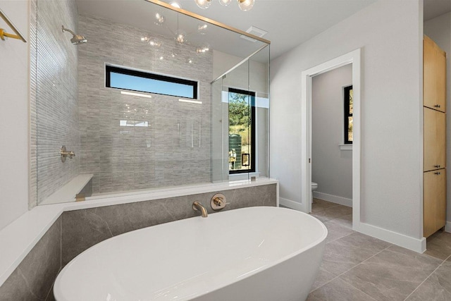 bathroom with a shower stall, toilet, a freestanding bath, tile patterned floors, and baseboards