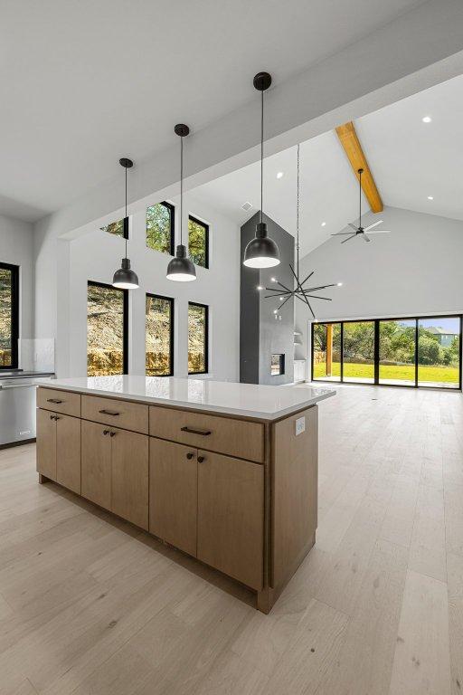 kitchen with beamed ceiling, plenty of natural light, light countertops, high vaulted ceiling, and ceiling fan