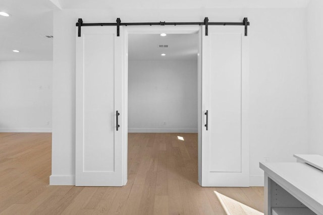 19634 Thurman Bend Rd, Spicewood, TX 78669 - hall featuring a barn door, recessed lighting, and light wood finished floors