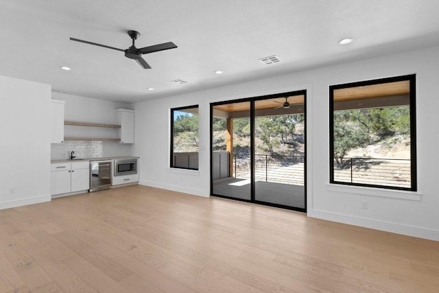19634 Thurman Bend Rd, Spicewood, TX 78669 - unfurnished living room featuring beverage cooler, a ceiling fan, light wood-type flooring, and recessed lighting