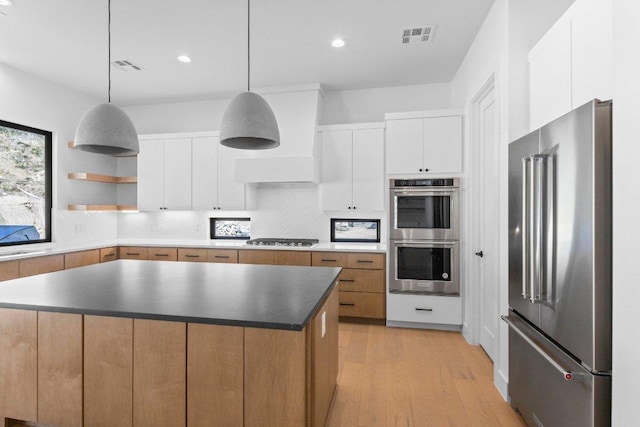 19634 Thurman Bend Rd, Spicewood, TX 78669 - kitchen featuring stainless steel appliances, decorative backsplash, light wood-style flooring, a kitchen island, and white cabinets