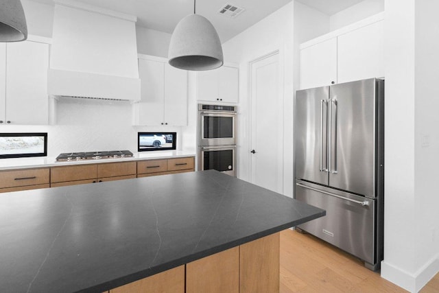 19634 Thurman Bend Rd, Spicewood, TX 78669 - kitchen with appliances with stainless steel finishes, light wood-type flooring, tasteful backsplash, white cabinetry, and decorative light fixtures