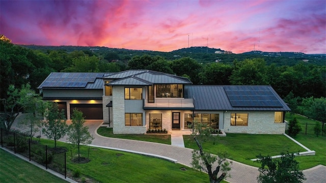 302 Bent Tree Ct, West Lake Hills, TX 78746 - back of property at dusk featuring a standing seam roof, stone siding, and roof mounted solar panels