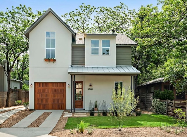 1406 Cometa St Unit 1, Austin, TX 78721 - view of front of home with fence, a garage, concrete driveway, a standing seam roof, and stucco siding