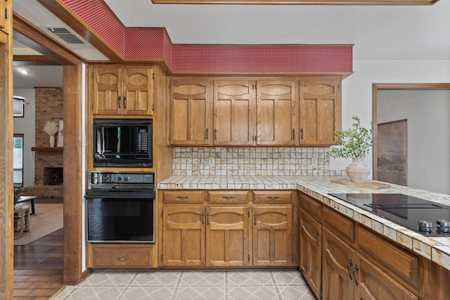 2821 Creek Side Dr, Temple, TX 76502 - kitchen with black appliances, tile counters, and decorative backsplash