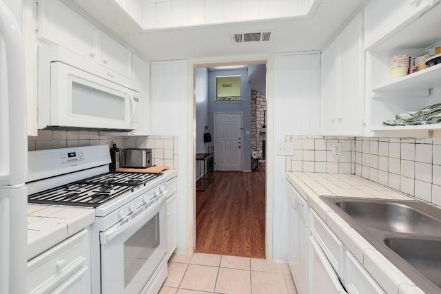 kitchen featuring white appliances, tile countertops, open shelves, a sink, and white cabinetry