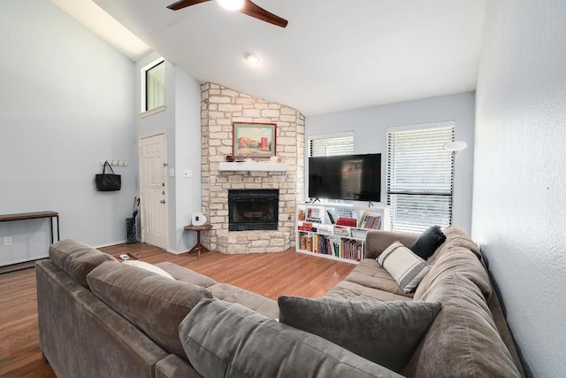 living room with a ceiling fan, a fireplace, vaulted ceiling, and wood finished floors