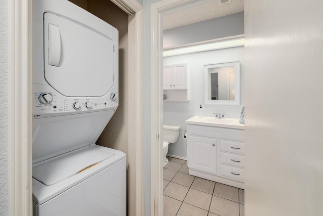 laundry room featuring stacked washer and clothes dryer and light tile patterned floors