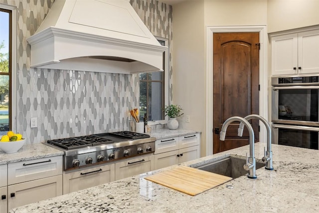 308 Duckhorn Pass, Austin, TX 78738 - kitchen with custom exhaust hood, stainless steel appliances, a sink, backsplash, and light stone countertops
