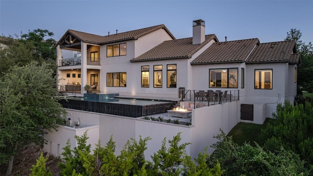 308 Duckhorn Pass, Austin, TX 78738 - back of house featuring a balcony, a chimney, a tiled roof, and stucco siding