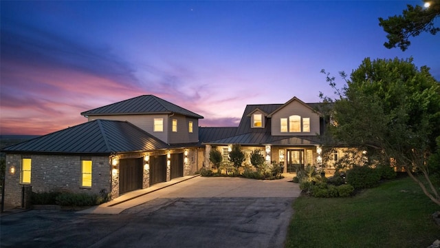 1071 Escalar Dr, Buchanan Dam, TX 78609 - view of front facade featuring a standing seam roof, concrete driveway, stone siding, metal roof, and an attached garage