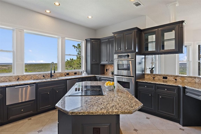 1071 Escalar Dr, Buchanan Dam, TX 78609 - kitchen featuring stainless steel appliances, a sink, a warming drawer, light tile patterned floors, and a center island
