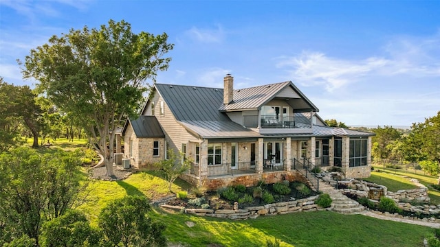 1071 Escalar Dr, Buchanan Dam, TX 78609 - rear view of house featuring a standing seam roof, a balcony, metal roof, a chimney, and a yard