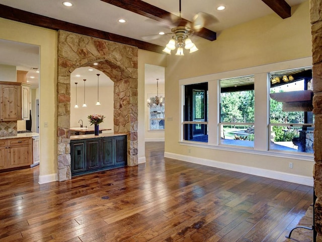 123 County Rd, Paige, TX 78659 - unfurnished living room with beam ceiling, dark wood finished floors, ceiling fan, arched walkways, and baseboards