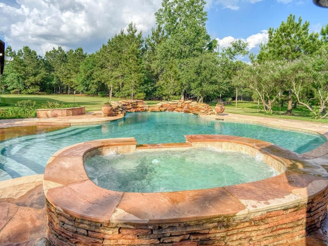 123 County Rd, Paige, TX 78659 - view of swimming pool featuring a pool with connected hot tub, view of wooded area, and a lawn