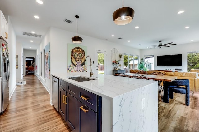 8603 Big Horn Cir, Lago Vista, TX 78645 - kitchen featuring light wood-type flooring, appliances with stainless steel finishes, pendant lighting, recessed lighting, and light stone countertops