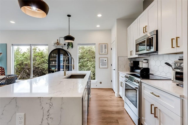8603 Big Horn Cir, Lago Vista, TX 78645 - kitchen with appliances with stainless steel finishes, backsplash, light wood-style floors, white cabinetry, and recessed lighting