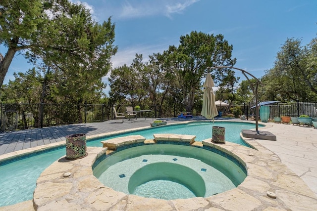 9201 Silver Pine Cv, Austin, TX 78733 - view of swimming pool with a pool with connected hot tub, a wooden deck, a fenced backyard, and view of wooded area