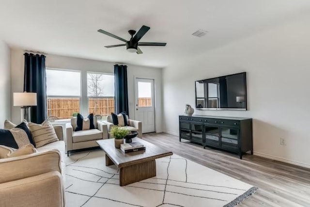 living area with a ceiling fan, light wood-style flooring, and baseboards