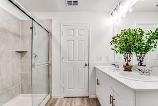 full bath featuring a stall shower, wood finished floors, and double vanity