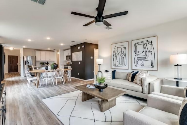living room with a ceiling fan, light wood-type flooring, recessed lighting, and baseboards