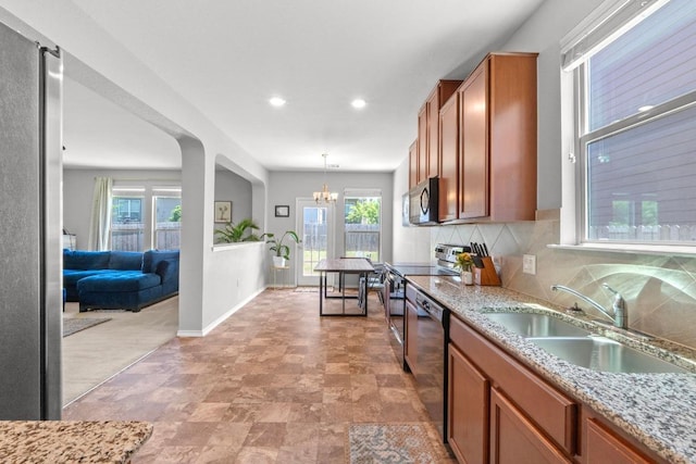 806 Sawbuck Dr, Pflugerville, TX 78660 - kitchen with appliances with stainless steel finishes, a chandelier, backsplash, light stone counters, and brown cabinets