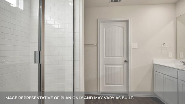 full bath featuring vanity, tiled shower, and baseboards