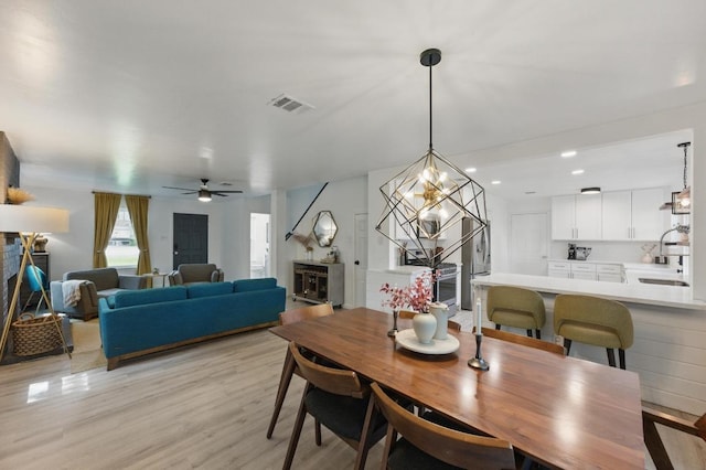 8805 Ravello Pass, Austin, TX 78749 - dining area featuring ceiling fan, light wood finished floors, recessed lighting, a chandelier, and a fireplace