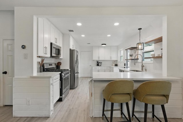 8805 Ravello Pass, Austin, TX 78749 - kitchen featuring appliances with stainless steel finishes, a sink, light wood-type flooring, a kitchen breakfast bar, and recessed lighting