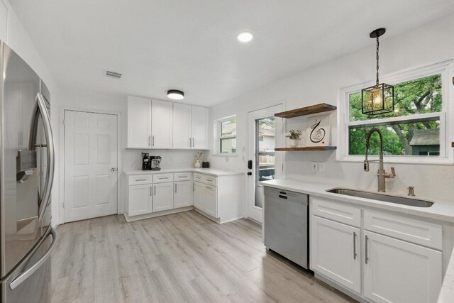 8805 Ravello Pass, Austin, TX 78749 - kitchen with stainless steel appliances, a sink, light wood-type flooring, white cabinetry, and light countertops