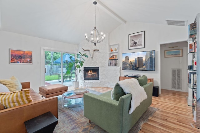 living room featuring wood finished floors, a chandelier, a stone fireplace, and baseboards