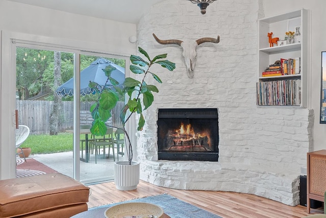 living room featuring wood finished floors, a fireplace, and lofted ceiling