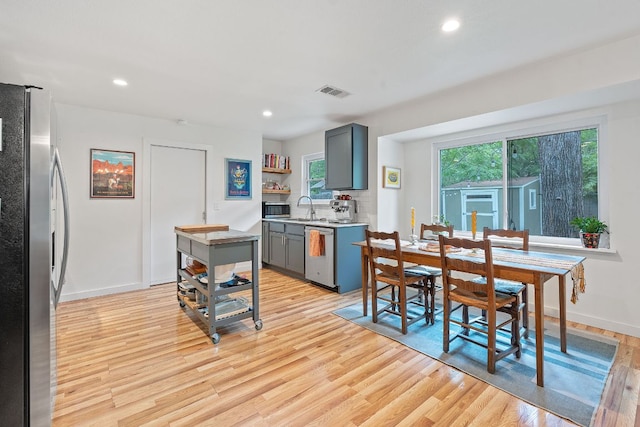 kitchen with appliances with stainless steel finishes, light wood-style floors, open shelves, gray cabinets, and recessed lighting