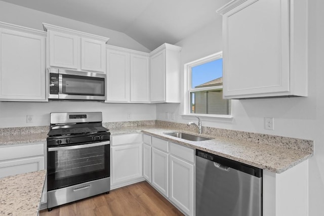 464 Aplite Pass, Maxwell, TX 78656 - kitchen with appliances with stainless steel finishes, a sink, lofted ceiling, white cabinetry, and light wood-style floors
