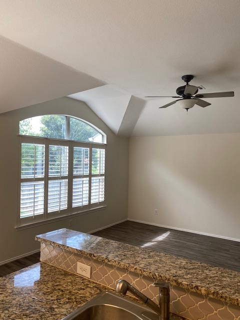 kitchen featuring dark wood finished floors, baseboards, lofted ceiling, ceiling fan, and a sink