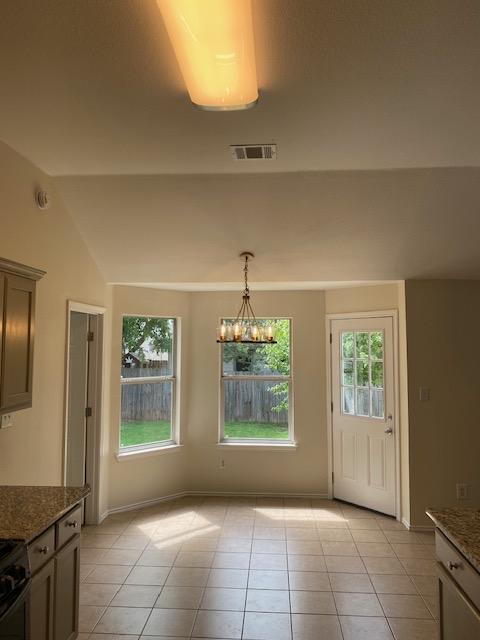 unfurnished dining area with light tile patterned floors, baseboards, a chandelier, and lofted ceiling