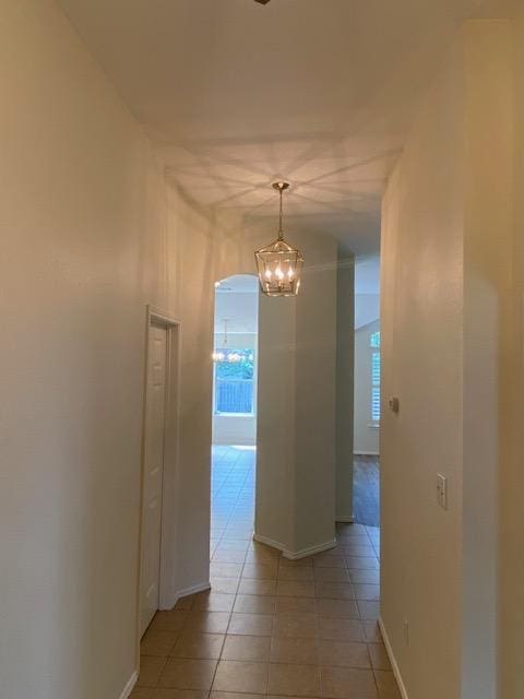 hallway featuring a chandelier, light tile patterned floors, and baseboards