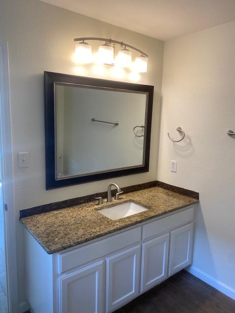 bathroom with vanity, wood finished floors, and baseboards