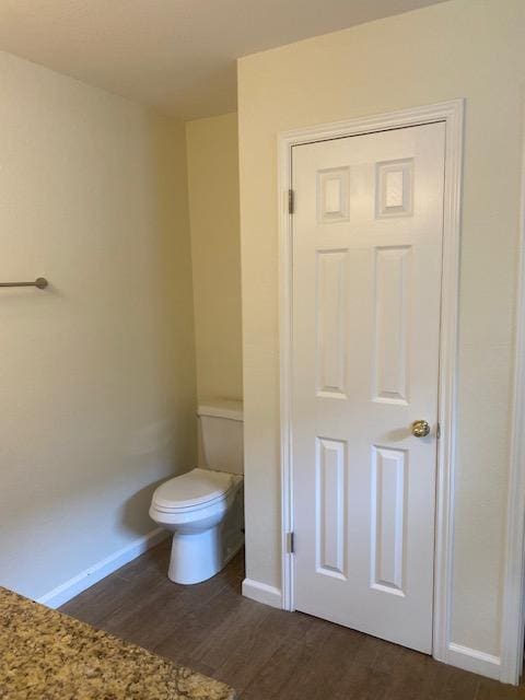 bathroom featuring wood finished floors, toilet, and baseboards
