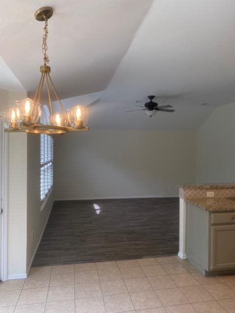 unfurnished dining area featuring a chandelier, vaulted ceiling, ceiling fan, and baseboards