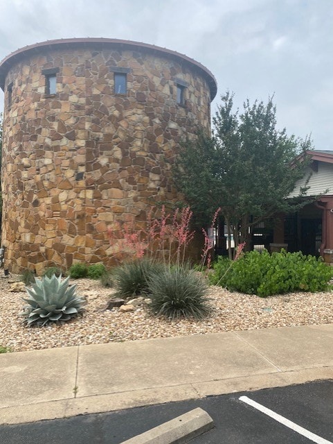 view of side of home featuring uncovered parking and stone siding