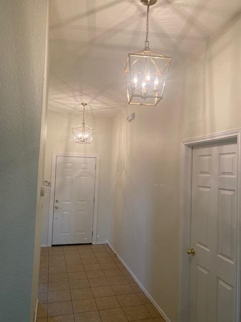 entryway featuring a chandelier, baseboards, and tile patterned flooring