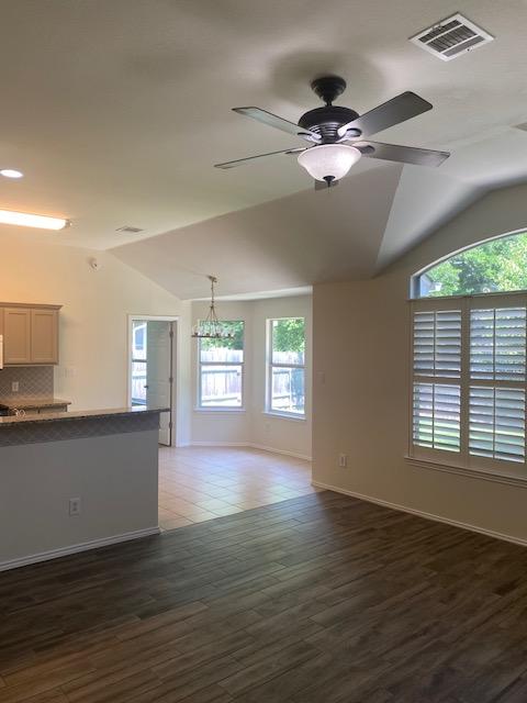unfurnished living room featuring lofted ceiling, healthy amount of natural light, baseboards, a ceiling fan, and wood finished floors